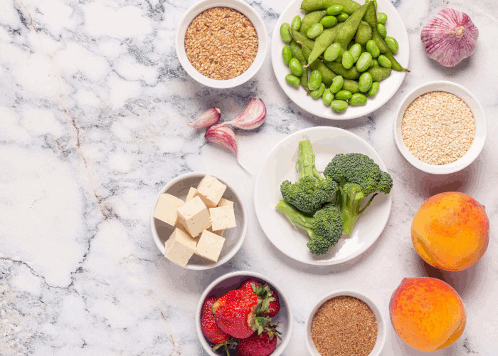 A selection of small white bowls placed on a marble surface containing pulses, rice and other raw vegetables